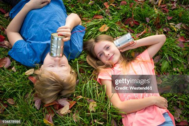 boy and girl on a meadow having fun with tin can phone - listening tin can stock pictures, royalty-free photos & images