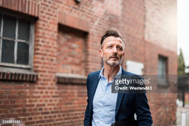 portrait of mature businessman at brick building - mature adult focus on foreground stock-fotos und bilder