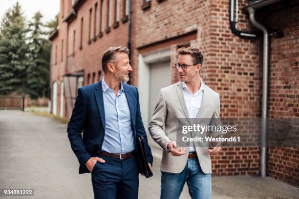 two businessmen talking at brick building - businesswear stock pictures, royalty-free photos & images