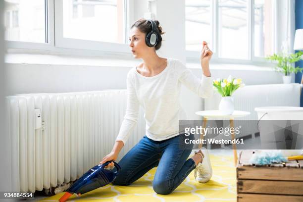 woman at home wearing headphones hoovering the floor - woman cleaning stock pictures, royalty-free photos & images