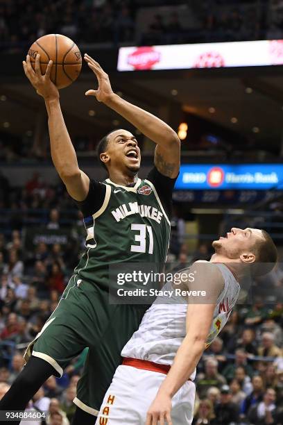 John Henson of the Milwaukee Bucks shoots over Mike Muscala of the Atlanta Hawks during the second half of a game at the Bradley Center on March 17,...