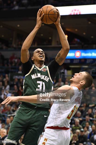 John Henson of the Milwaukee Bucks shoots over Mike Muscala of the Atlanta Hawks during the second half of a game at the Bradley Center on March 17,...