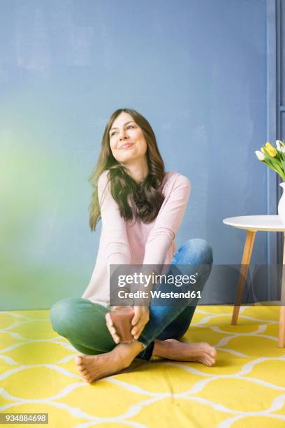 smiling woman sitting on floor holding glass of juice - die besten im fruehling stock-fotos und bilder