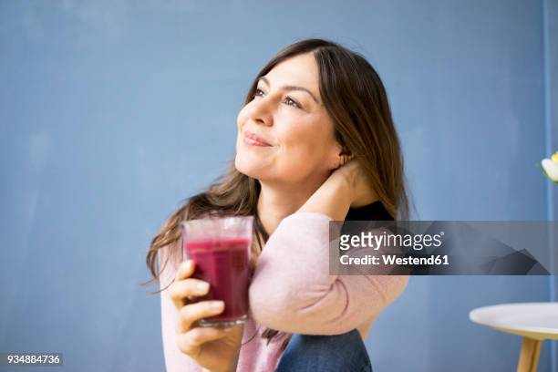 smiling woman holding glass of juice - drinking juice stock-fotos und bilder