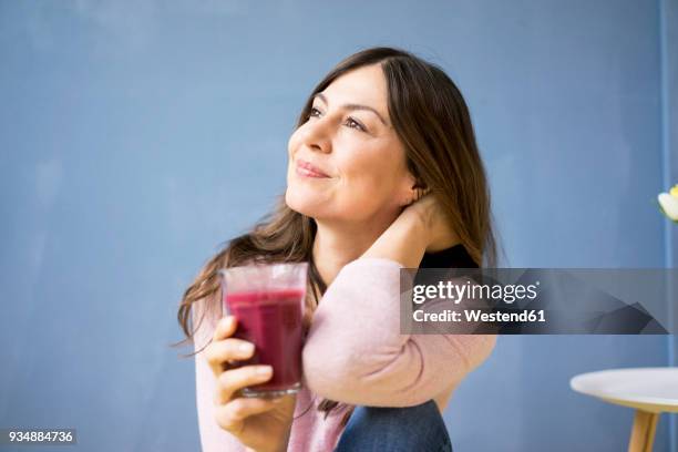 smiling woman holding glass of juice - woman smoothie stock pictures, royalty-free photos & images