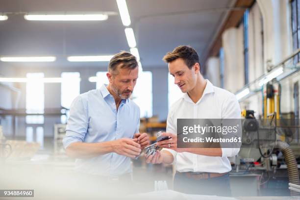 two businessmen in factory discussing product - objekt stock-fotos und bilder