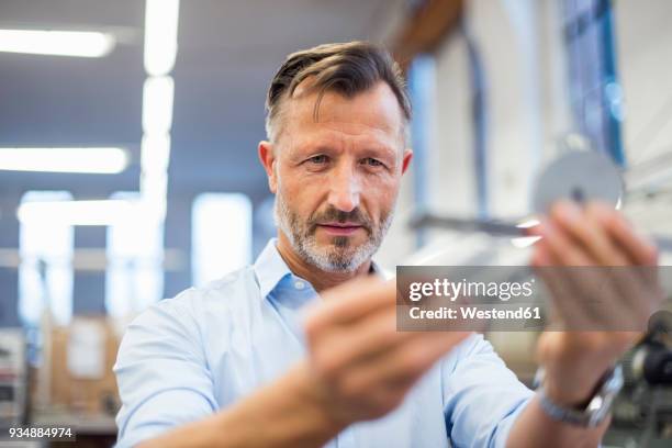 mature businessman in factory examining component - bildschärfe stock-fotos und bilder