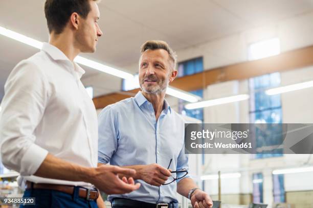 two businessmen discussing in factory - faccia a faccia foto e immagini stock