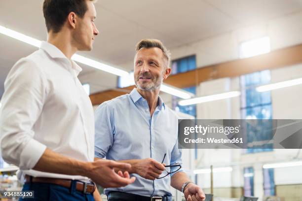 two businessmen discussing in factory - rolling up sleeve stock pictures, royalty-free photos & images