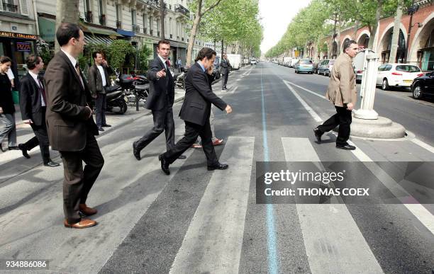 French right-wing UMP presidential candidate Nicolas Sarkozy crosses the street as he walks toward a shelter for women, 23 April 2007 in Paris, a day...