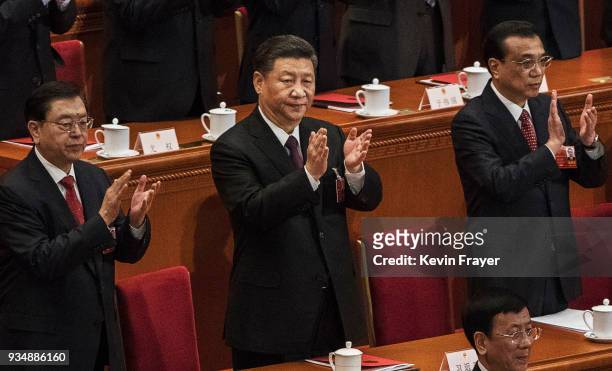 China's President Xi Jinping, center, applauds as he stands next to Premier Li Keqiang, right, and others after his speech to the closing session of...