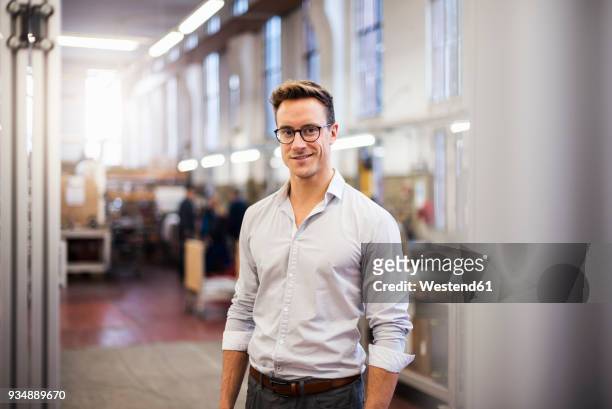 portrait of smiling young businessman in factory - overhemd man stockfoto's en -beelden