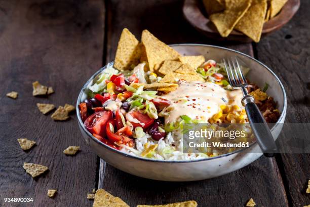 taco salad bowl with rice, corn, chili con carne, kidney beans, iceberg lettuce, sour cream, nacho chips, tomatoes - bowl of chili stock-fotos und bilder