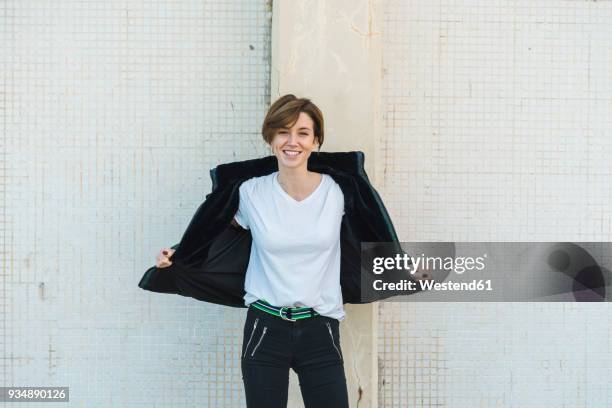 portrait of relaxed woman taking off her jacket - weiße jacke stock-fotos und bilder