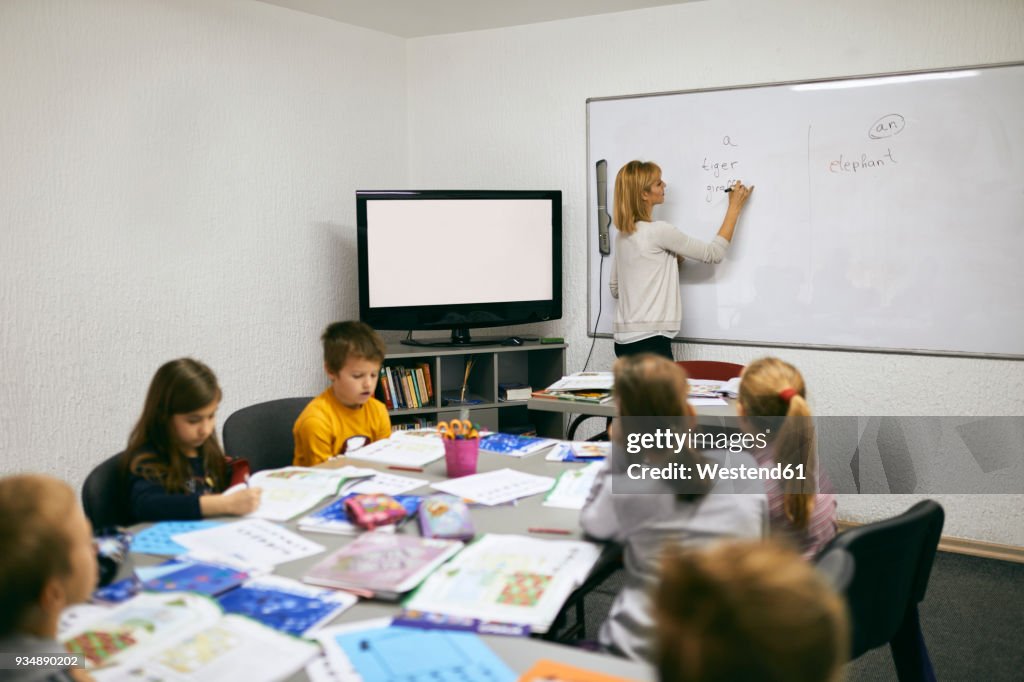 Teacher writing on whiteboard in class