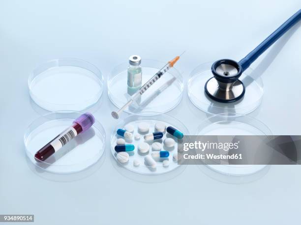 stethoscope, vaccine, blood sample and variety of medicine in petri dish - syringe full of blood stockfoto's en -beelden