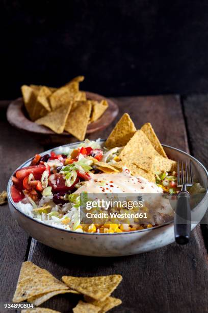 taco salad bowl with rice, corn, chili con carne, kidney beans, iceberg lettuce, sour cream, nacho chips, tomatoes - taco salad stock pictures, royalty-free photos & images