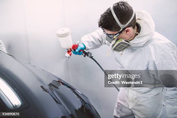 auto painter painting a car inside a paint booth - pistola de pintura imagens e fotografias de stock