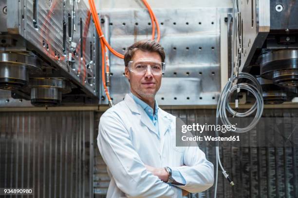 portrait of man wearing lab coat and safety goggles at machine - scientist portrait stock pictures, royalty-free photos & images