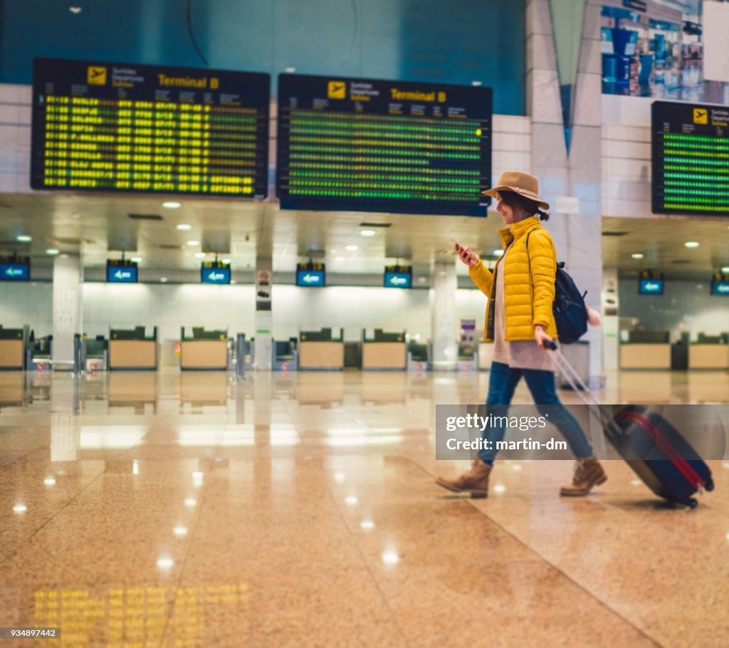 Junge Frau mit Smartphone am Flughafen-terminal