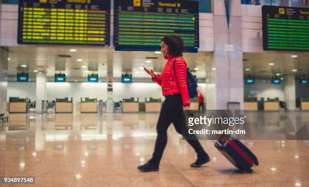 mixed race woman texting at the airport terminal - france v united states imagens e fotografias de stock