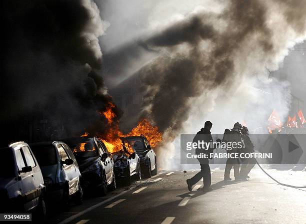 Firemen run towards torched cars after clashes throughout the Swiss city of Geneva on November 28, 2009 during a demonstration against the upcoming...