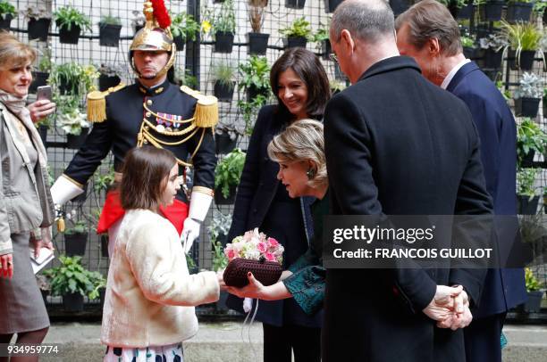 Child offers flowers to Grand Duchess Maria-Teresa of Luxembourg flanked by Grand Duke Henri of Luxembourg as Paris' mayor Anne Hidalgo and French...