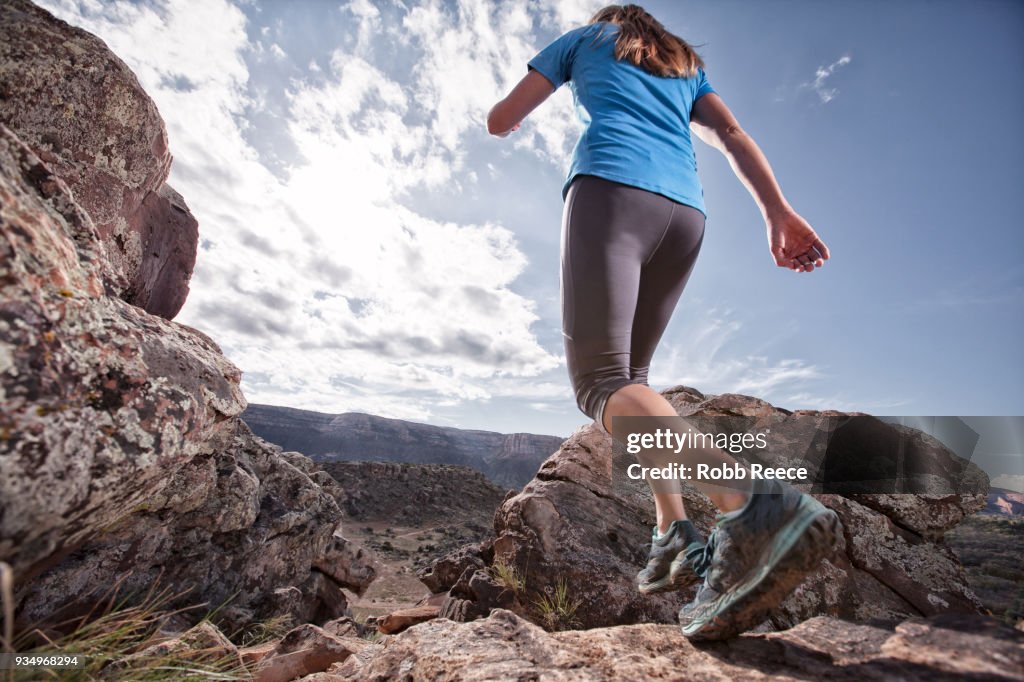 An adult woman trail running on a remote dirt trail