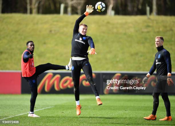 Jordan Pickford clears the ball as Joe Hart and Danny Welbeck watch on during an England training session at St Georges Park on March 20, 2018 in...