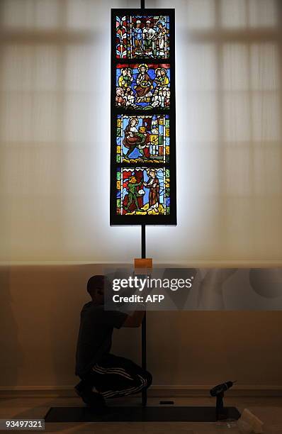 Man affixes a plaque below "Four Stained Glass Panels", about 1170-1180, from Troyes, France during the press preview of the new Medieval and...