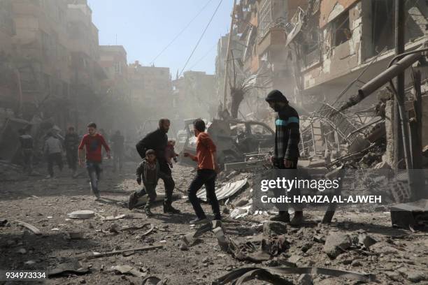 Syrians run for cover following Syrian government air strikes on the Eastern Ghouta rebel-held enclave of Douma, on the outskirts of the capital...