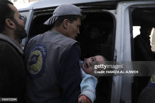 Syrian civil defence volunteer carries an injured infant following Syrian government air strikes on the Eastern Ghouta rebel-held enclave of Douma,...