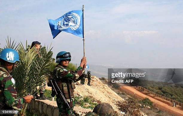 An Indonesian UNIFIL peacekeeper waves a UN flag on the border between Lebanon and Israel in the southern Lebanese village of Adaisseh on November...