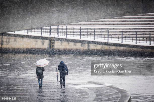 Two person walk during snow fall along the river Spree on March 20, 2018 in Berlin, Germany.