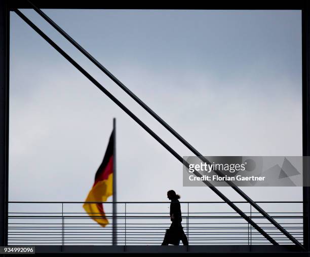 Woman walks across a bridge in front of the waving german flag on March 20, 2018 in Berlin, Germany.
