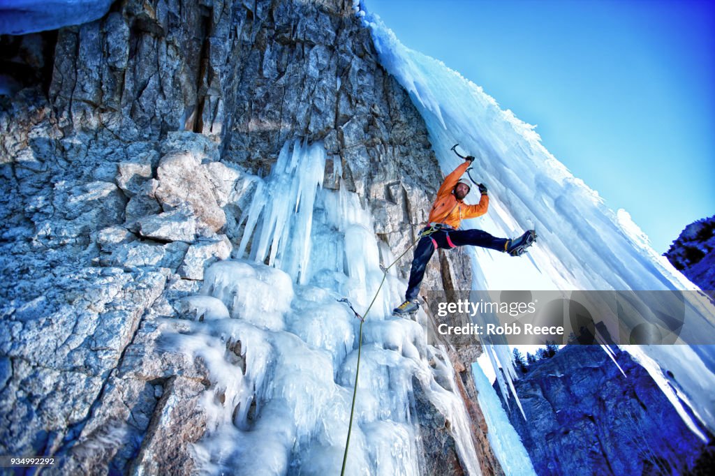 A male ice climber on a frozen waterfall