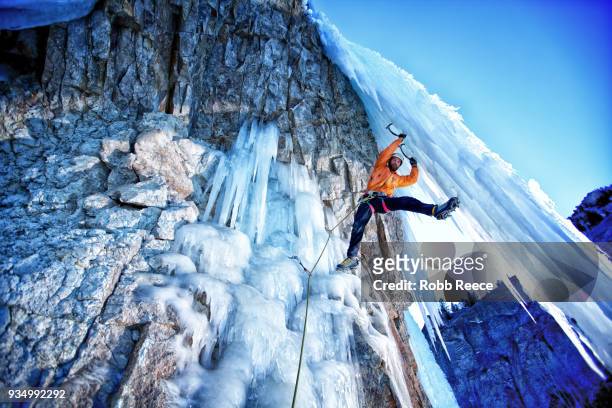 a male ice climber on a frozen waterfall - robb reece stock pictures, royalty-free photos & images
