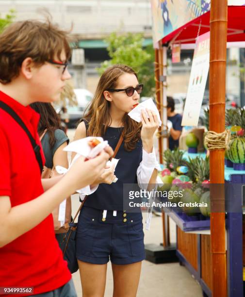 teenagers eating a mexican dessert- churros on the street. street food. - churro stockfoto's en -beelden