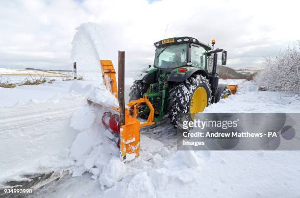 Farmer in a tractor helps to clear the snow from a blocked road heading out of Simonsbath in Exmoor National park, as the icy conditions brought by...