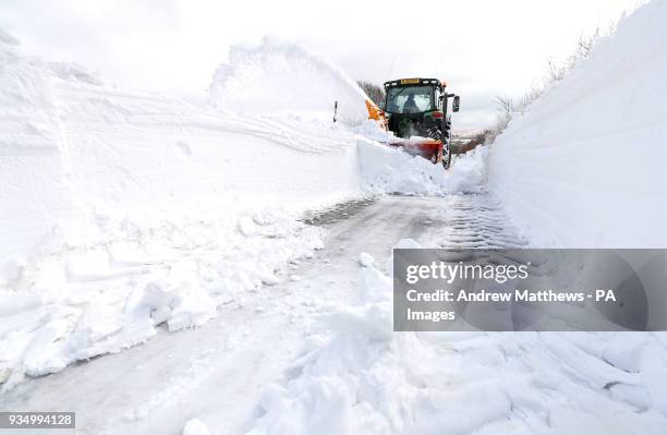 Farmer in a tractor helps to clear the snow from a blocked road heading out of Simonsbath in Exmoor National park, as the icy conditions brought by...