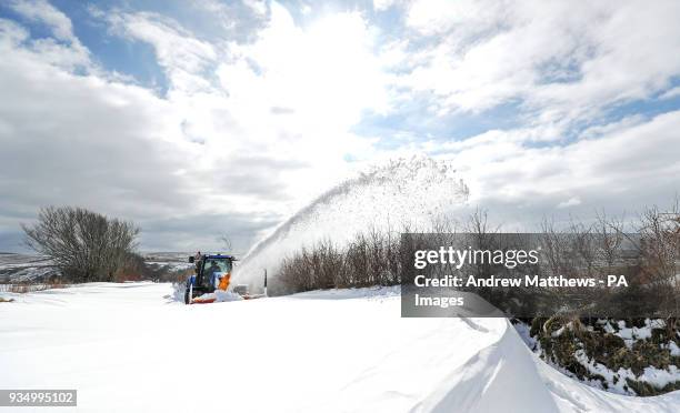 Farmer in a tractor helps to clear the snow from a blocked road heading out of Simonsbath in Exmoor National park, as the icy conditions brought by...