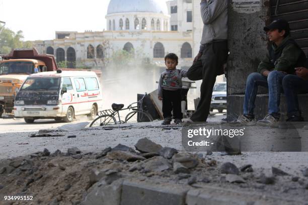 Civilians sit in a damaged street in the Eastern Ghouta town of Kafr Batna, on the northeastern outskirts of Damascus, on March 20, 2018.Government...