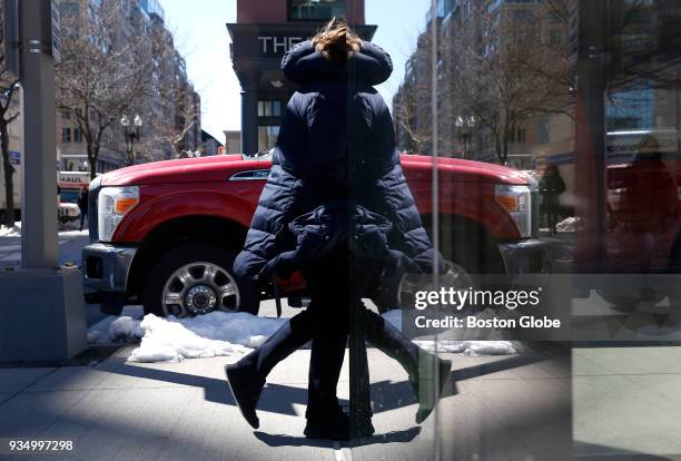Pedestrian in a winter jacket is reflected in a shop window on Boylston Street in Boston amid cold weather on the last day of winter, March 19, 2018.