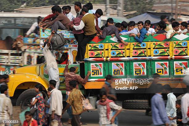 Bangladeshis climb into a truck at a bus station in Dhaka on November 27, 2009 as thousands of Muslims rush home to their families in remote villages...
