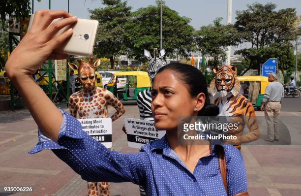 Woman takes a selfie with People for the Ethical Treatment of Animals members body-painted as a tiger, zebra and giraffe standing with signs...