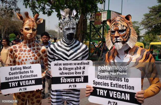 People for the Ethical Treatment of Animals members body-painted as a tiger, zebra and giraffe stand with signs promoting vegan eating ahead of...