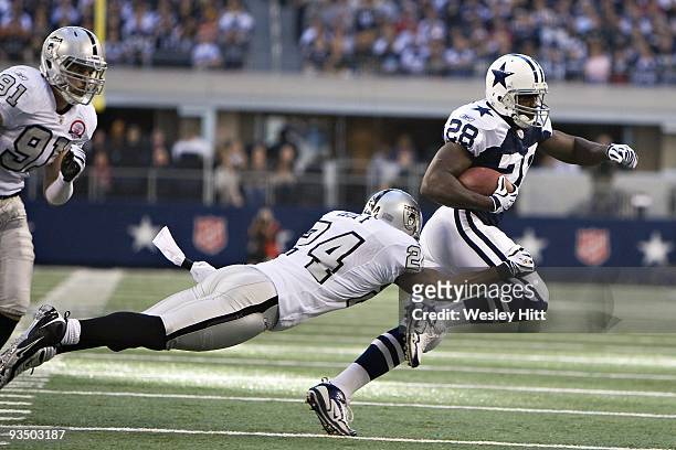 Running back Felix Jones of the Dallas Cowboys is tackled by defensive back Michael Huff of the Oakland Raiders at Cowboys Stadium on November 26,...