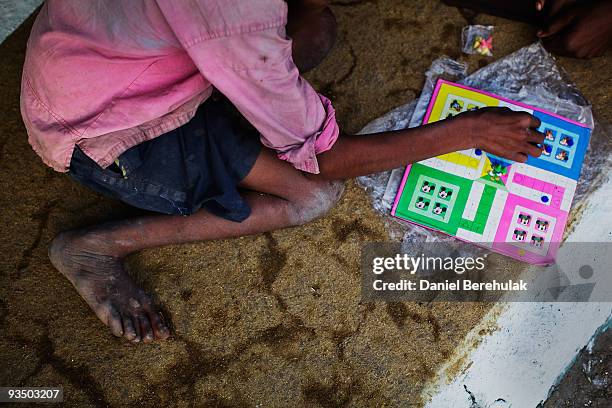 Fifteen year old Sachin Kumar plays a board game with his friends in a slum near the site of the deserted Union Carbide factory on November 29, 2009...