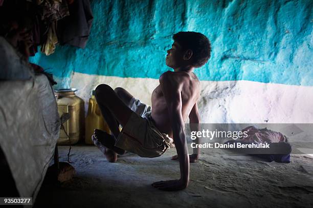 Fifteen year old Sachin Kumar crawls on his hands and knees through his home in a slum near the site of the deserted Union Carbide factory on...