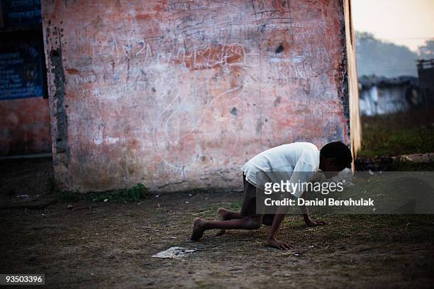Fifteen year old Sachin Kumar crawls on his hands and knees after playing a game of cricket with his friends in a slum near the site of the deserted...